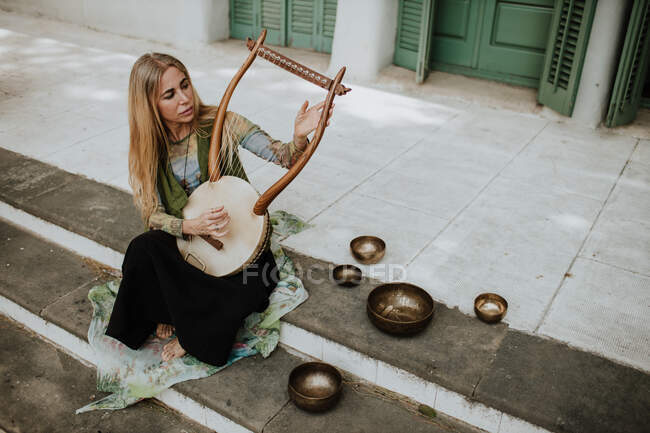 Женщина играет на лире на ступеньках — стоковое фото