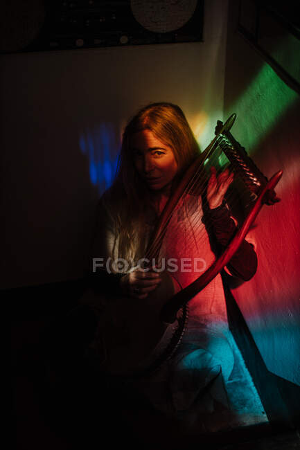 Mujer jugando lira bajo luz colorida - foto de stock