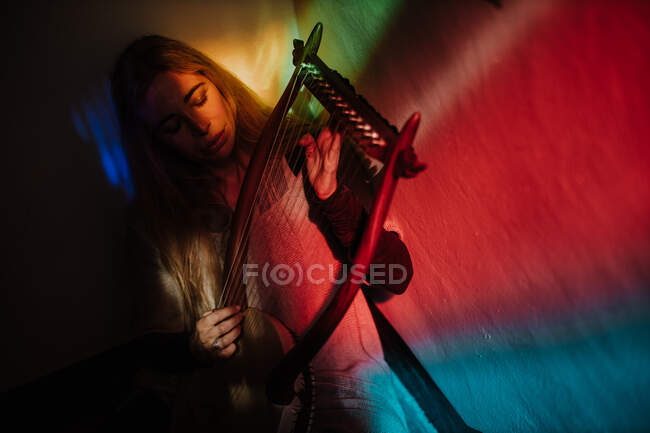 Женщина играет на лире под ярким светом — стоковое фото