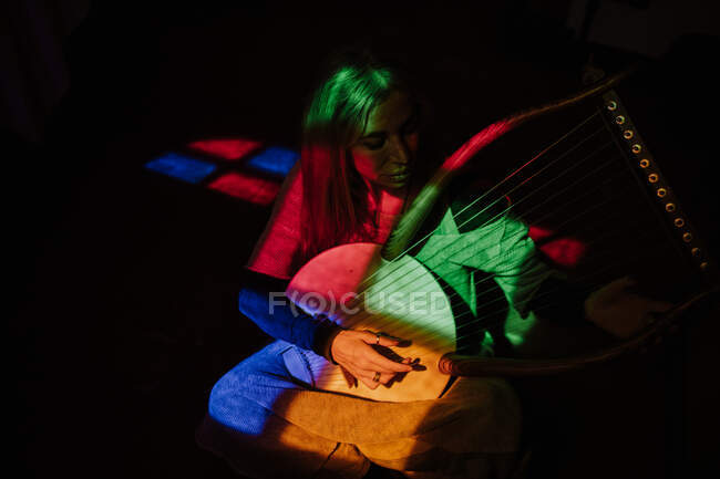 Frau spielt Leier unter buntem Licht — Stockfoto