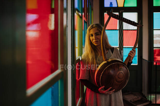 Женщина с лирой стоит возле витражей — стоковое фото