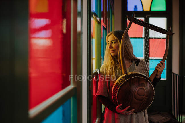 Femme avec lyre debout près des vitraux — Photo de stock