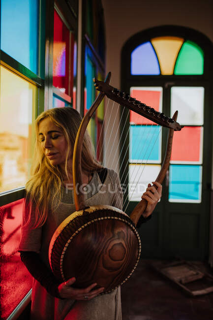 Woman with lyre standing near stained glass windows — Stock Photo