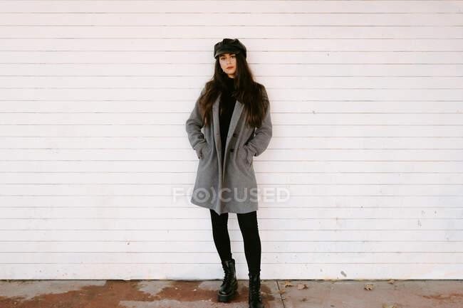 Confiante jeune femme près du mur blanc — Photo de stock