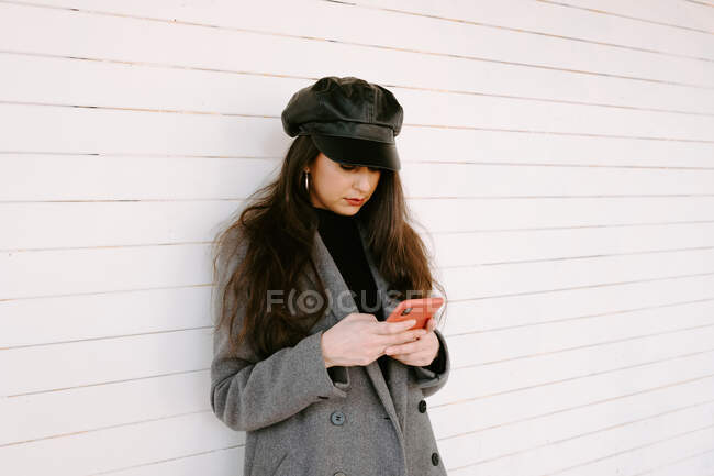 Mulher usando smartphone perto da parede — Fotografia de Stock