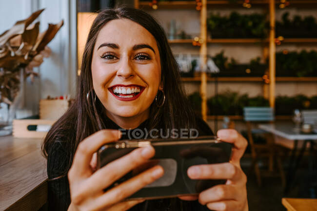 Junge Frau benutzt Smartphone im Café — Stockfoto