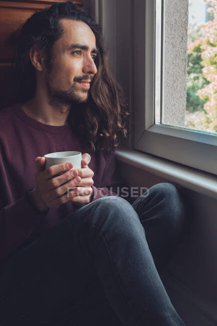 Adult male with mug looking out window — Stock Photo