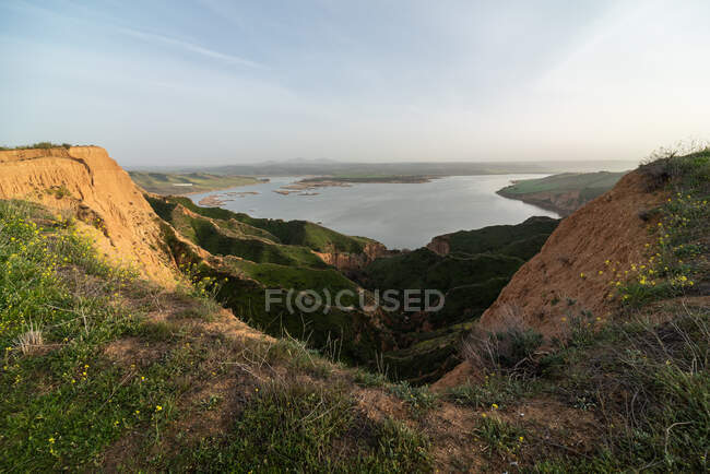Majestic view of grassy canyon and calm lake located against morning sky in countryside in Barrancas Burujon, Toledo, Spain — Stock Photo