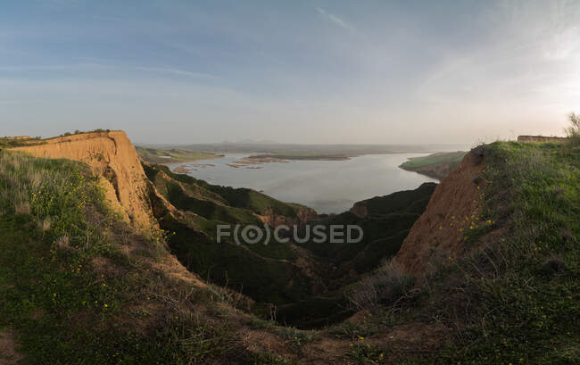 Majestic view of grassy canyon and calm lake located against morning sky in countryside in Barrancas Burujon, Toledo, Spain — Stock Photo