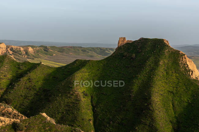 Verde collina erbosa nella giornata di sole in una natura tranquilla vicino antiche rovine torre — Foto stock