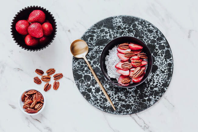 Top view of yummy sorbet with fresh strawberries and walnuts served in bowl on marble table near spoon — Stock Photo