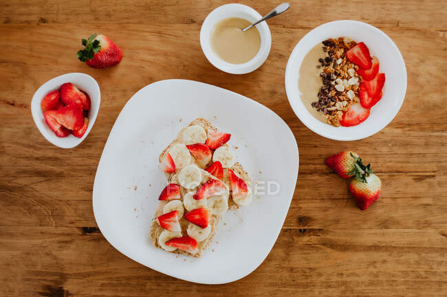Leckere Bananen-Erdbeer-Sandwiches mit süßem Püree auf Teller zum Frühstück auf Holztisch — Stockfoto
