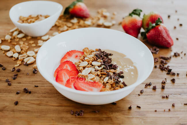 Closeup bowl of tasty sweet puree with strawberry and chocolate complemented with peanuts and walnuts and served for breakfast — Stock Photo