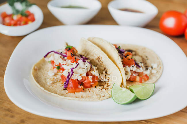 Tacos mexicains avec garniture de légumes servis avec des tranches de citron vert sur l'assiette — Photo de stock