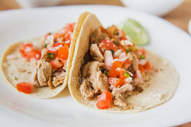 Leckere mexikanische Tacos mit Gemüsefüllung serviert mit Scheiben grüner Limette auf dem Teller auf dem Tisch — Stockfoto