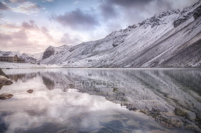 Lago calmo e montagna innevata sul cielo nuvoloso al tramonto nel Parco Nazionale Svizzero in Svizzera — Foto stock