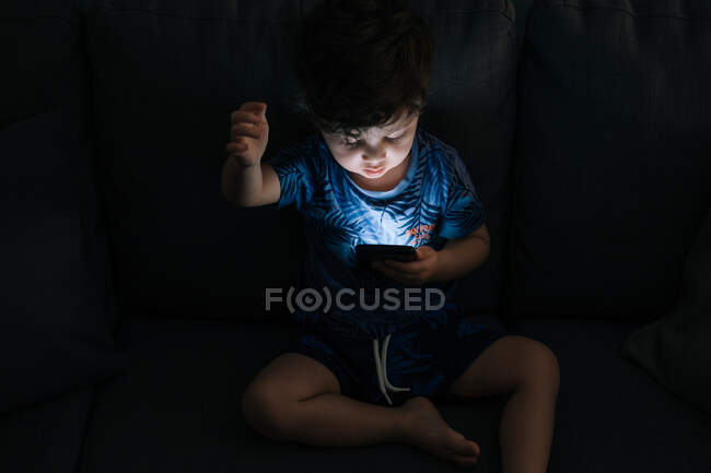 Любопытный маленький мальчик просматривает смартфон дома — стоковое фото