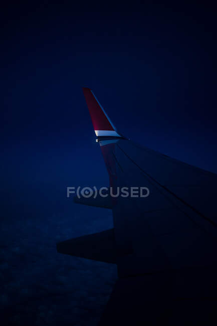 Através da visão da janela da asa do avião moderno voando sobre as nuvens na noite escura — Fotografia de Stock
