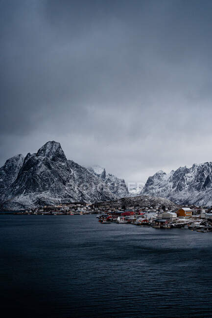 From above of city harbor against snowy mountain ridges at horizon in overcast weather in Norway — Stock Photo