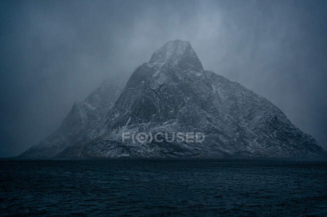 Breathtaking view of blue rippled sea water against snowy mountain ridges on shore under gray cloudy sky in wintertime in Norway — Stock Photo