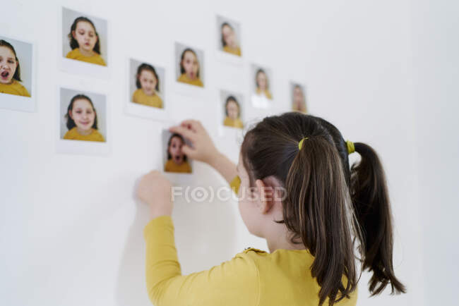 Una bella ragazza in un abito giallo mette le immagini di se stessa contro il muro mostrando varie emozioni — Foto stock