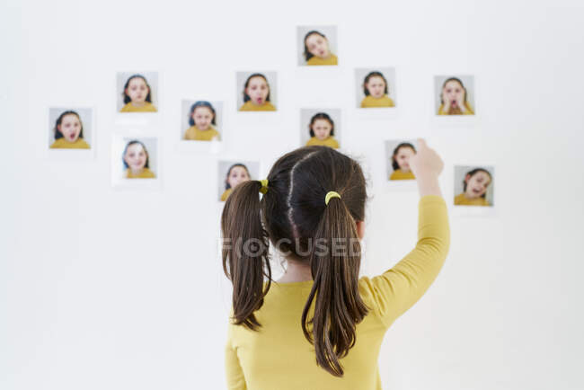 Carino bambina in un abito giallo è in piedi sulla schiena mettendo foto di se stessa mostrando varie emozioni — Foto stock