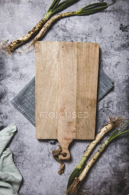 Draufsicht auf ein Bündel reifer, schmutziger Calsot-Zwiebeln auf Tablett und Leinentuch auf einem Holztisch in der Nähe von Messer in Katalonien, Spanien — Stockfoto