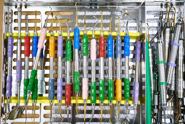 Vista superior del kit de curettes limpios con manijas coloridas colocadas en bandeja de metal en laboratorio - foto de stock