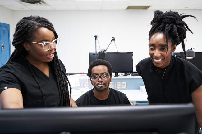Donne nere e uomo in uniforme discutono i dati sul computer mentre lavorano insieme nel laboratorio contemporaneo — Foto stock