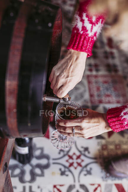 Von oben anonymer Verkäufer, der Glasbecher mit Wein vom Fass füllt, während er im örtlichen Lebensmittelgeschäft arbeitet — Stockfoto