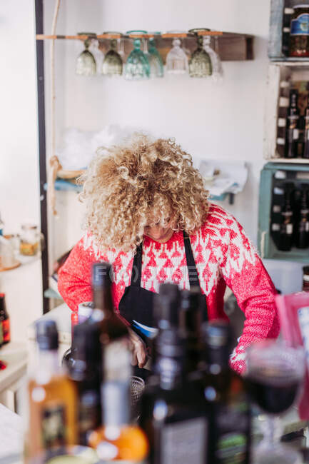 Friendly adult woman with curly hair working in cozy local delicatessen food shop — Stock Photo