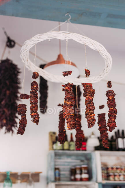 Снизу куски вкусного сушеного мяса висят на веревках с потолка в уютном местном продуктовом магазине — стоковое фото
