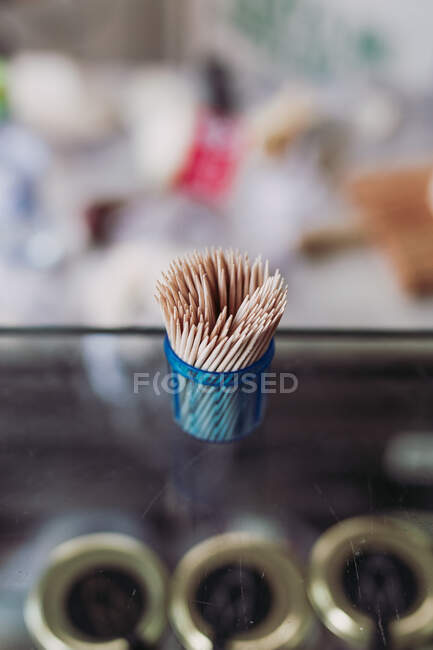 Dall'alto stuzzicadenti bastone di legno in un piccolo contenitore blu su sfondo sfocato — Foto stock