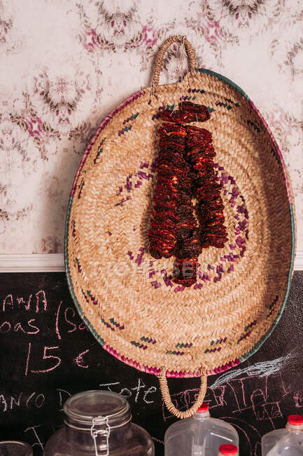 Pieces of delicious dried meat hanging on straw tray on a wall in cozy local delicatessen food store — Stock Photo