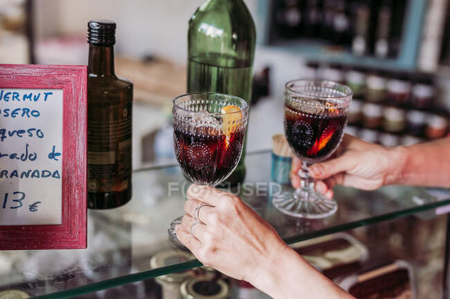 Засеянная неузнаваемая барменша с чашкой стаканов со свежим алкогольным напитком во время работы в местном магазине деликатесов — стоковое фото