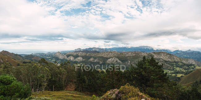 Green valley scene with mountains and cloudy sky — Stock Photo