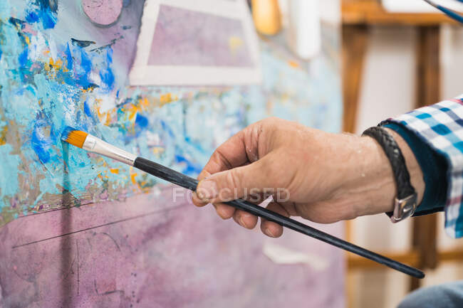 Aged man painting picture with brush — Stock Photo