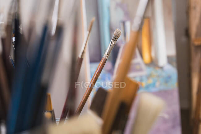 Many paintbrushes in glass on table — Stock Photo