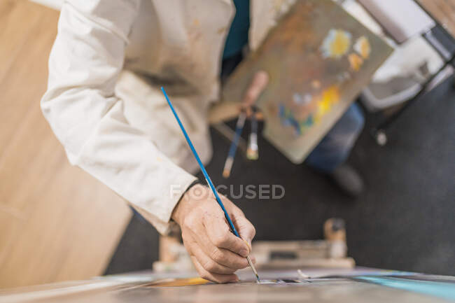 У віці чоловік малює картину пензлем — стокове фото