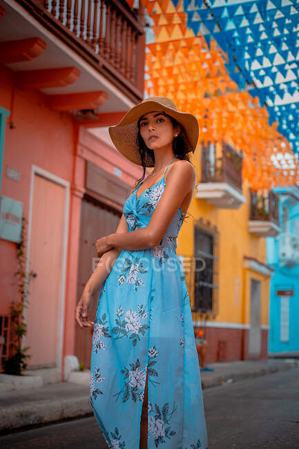 Elegante donna in abito estivo in piedi vicino edificio colorato — Foto stock