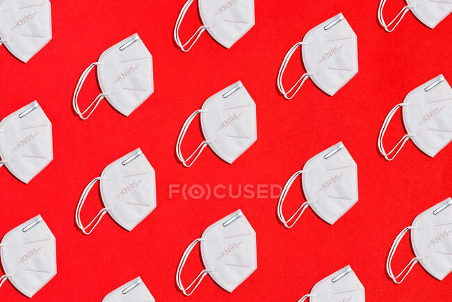 Collage de certains masques blancs pour le facteur de protection KN95 sur fond rouge vue zénith — Photo de stock