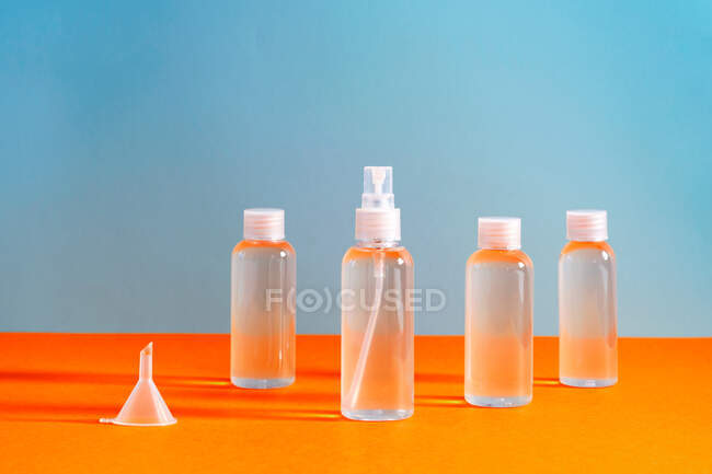 Несколько прозрачных бутылок с соляным гелем вместе с воронкой для заполнения служит для дезинфекции рук ковид-19 — стоковое фото