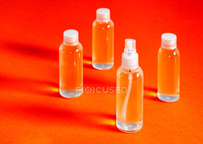 Несколько прозрачных бутылок с соляным гелем вместе с воронкой для заполнения служит для дезинфекции ковид-19 's руки вид сверху — стоковое фото