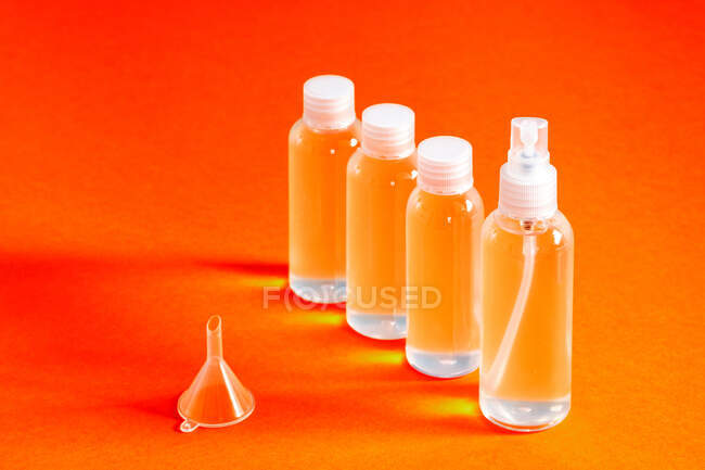 Diverse bottiglie trasparenti con gel cloridrico insieme a un imbuto da riempire serve a disinfettare la vista dall'alto delle mani di covid-19 — Foto stock