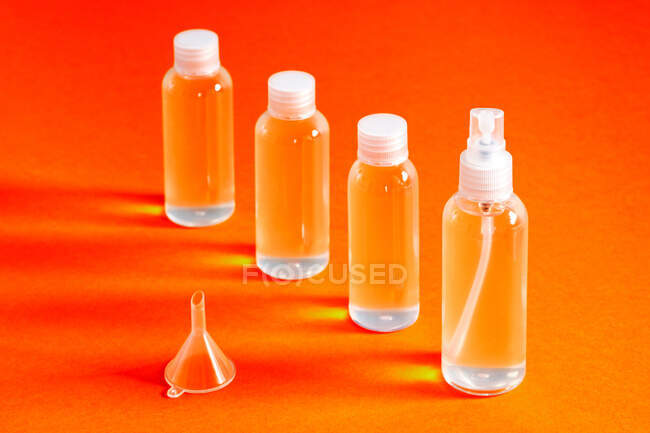 Several clear bottles with hydrochloric gel along with a funnel to fill serves to disinfect covid-19's hands top view — Stock Photo