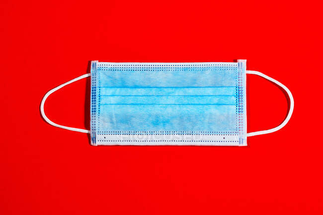 Blaue Einmalmaske für Virenschutz auf rotem Hintergrund — Stockfoto