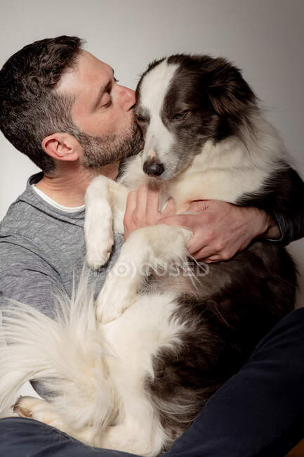 Uomo in abito casual che dà abbraccio e bacio all'amato cane Border Collie a casa — Foto stock