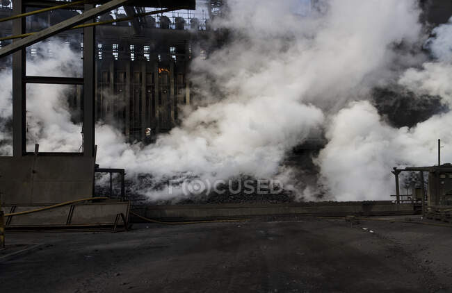 Piles of coke emitting thick smoke after process of cooling with cold water at quenching tower of coking plant — Stock Photo