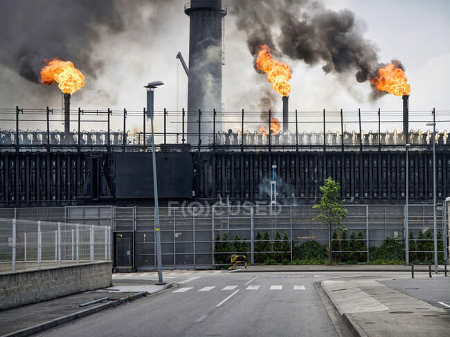 Погодні промислові будівлі і труби, що випускають дим і полум'я на коксохімічному заводі — стокове фото