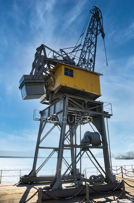 Angolo basso della gru container contemporanea situato sul molo nel porto di San Esteban de Pravia contro il cielo blu nuvoloso nella giornata di sole in Spagna — Foto stock